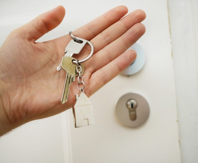 Photo d'une main avec des clés devant une porte